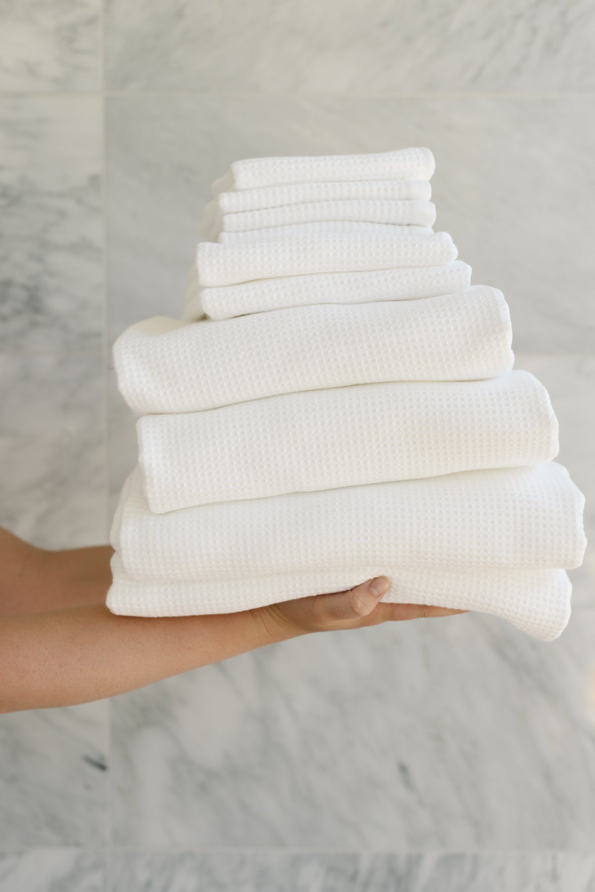 Complete Waffle Bath Bundle in the color White. Photo of White Complete Waffle Bath Bundle taken while being held by a persons outreached hands 