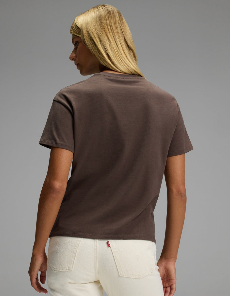 A person with straight blonde hair wears the Cozy Earth Women’s All Day Tee in brown and off-white jeans, standing with their back to the camera against a plain gray background.|Color:Cacao