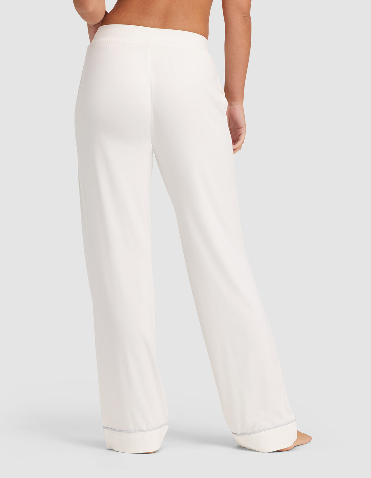 A person is shown from the waist down wearing HIDE Women's Bamboo Stretch-Knit Pajama Pant in white, featuring a wide waistband, relaxed straight-leg fit, and lightly pooled hems against a plain light-colored background. |Color:Ivory