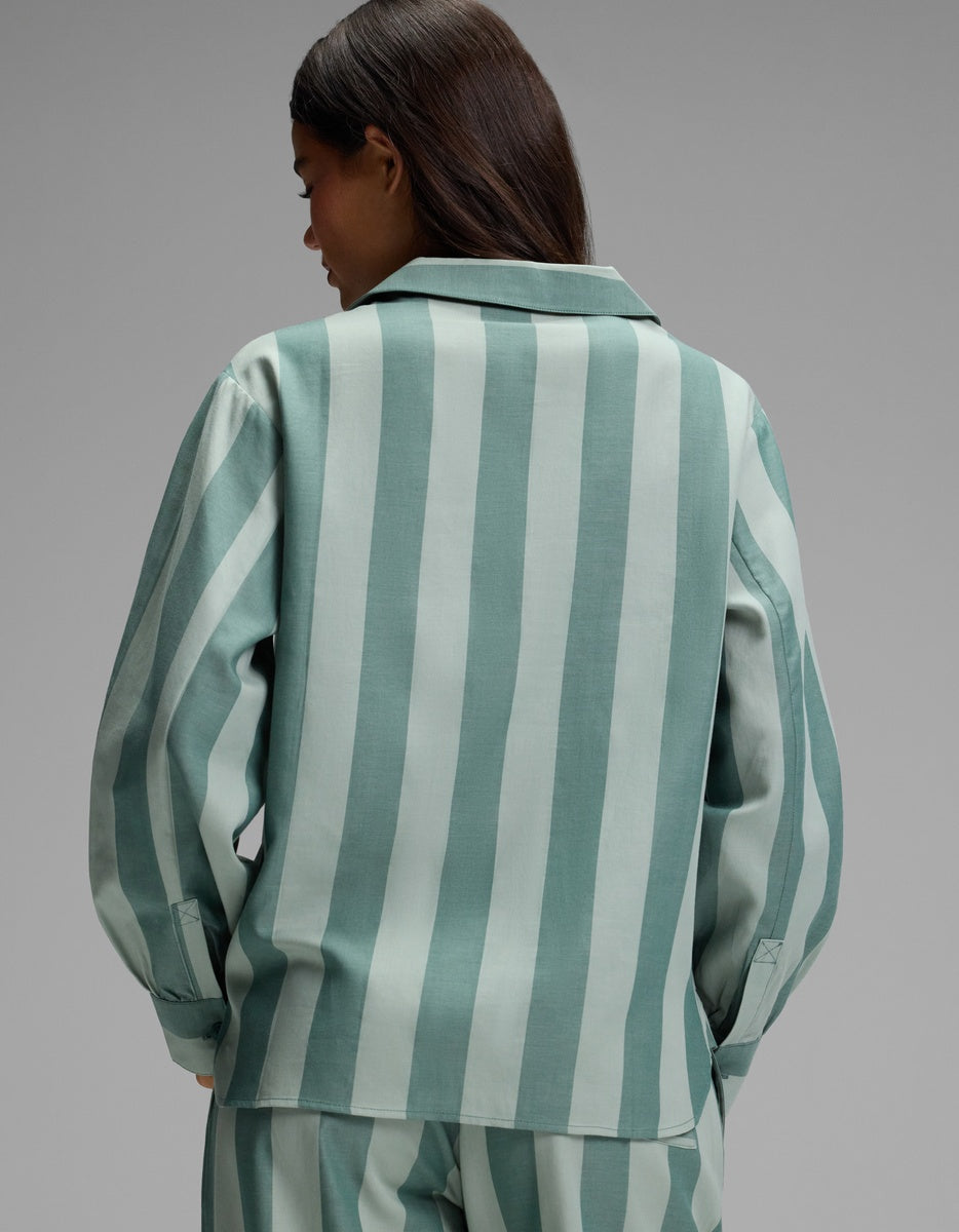 A person with long dark hair is shown from the back, wearing the Cozy Earth Women’s Belmont Long Sleeve Pajama Top in a light green and white vertical stripe pattern, set against a plain gray background.|Color:Rosemary Stripe
