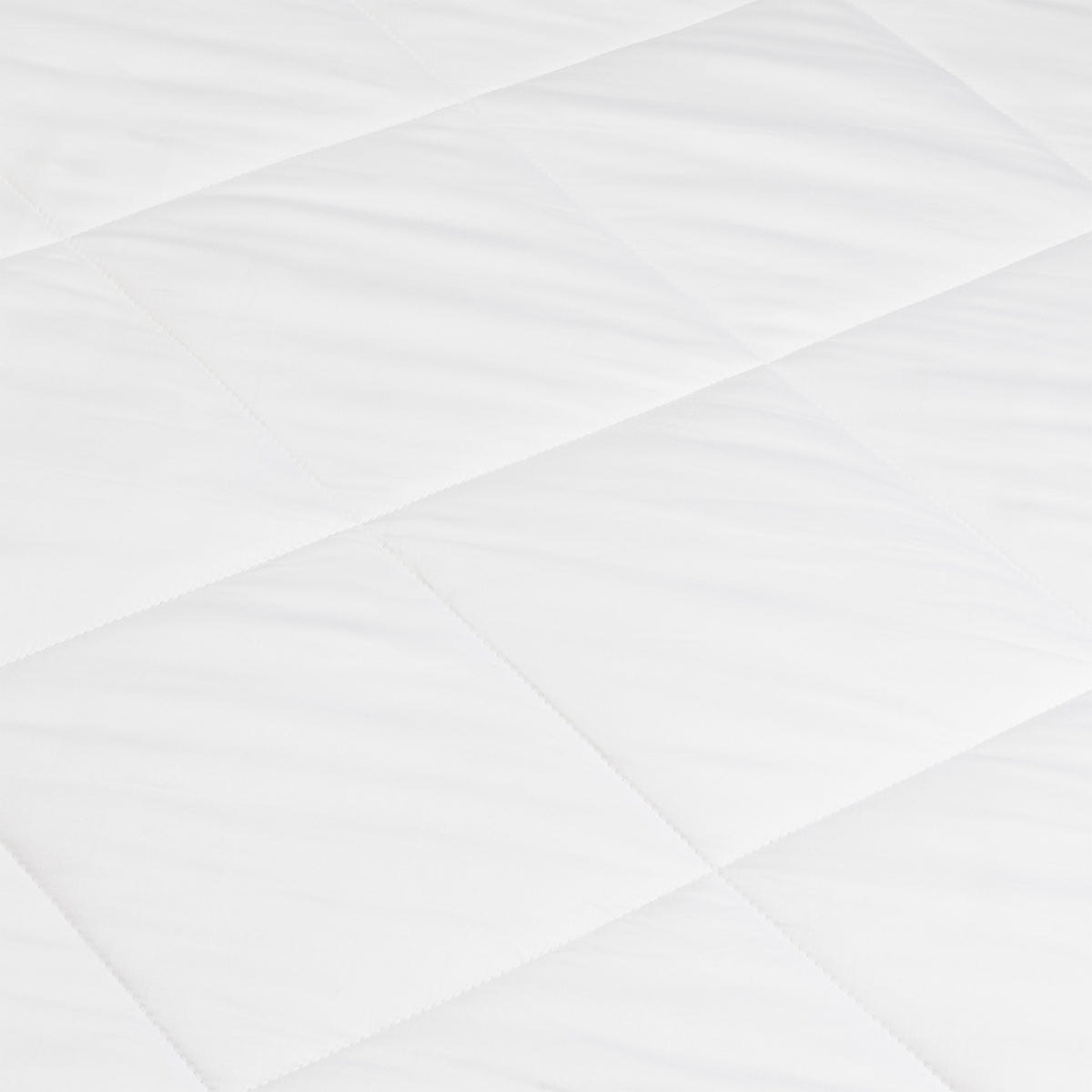 A close-up of the Cozy Earth Bamboo Viscose Comforter shows its smooth, soft white quilted fabric with a diamond pattern formed by intersecting stitched lines.