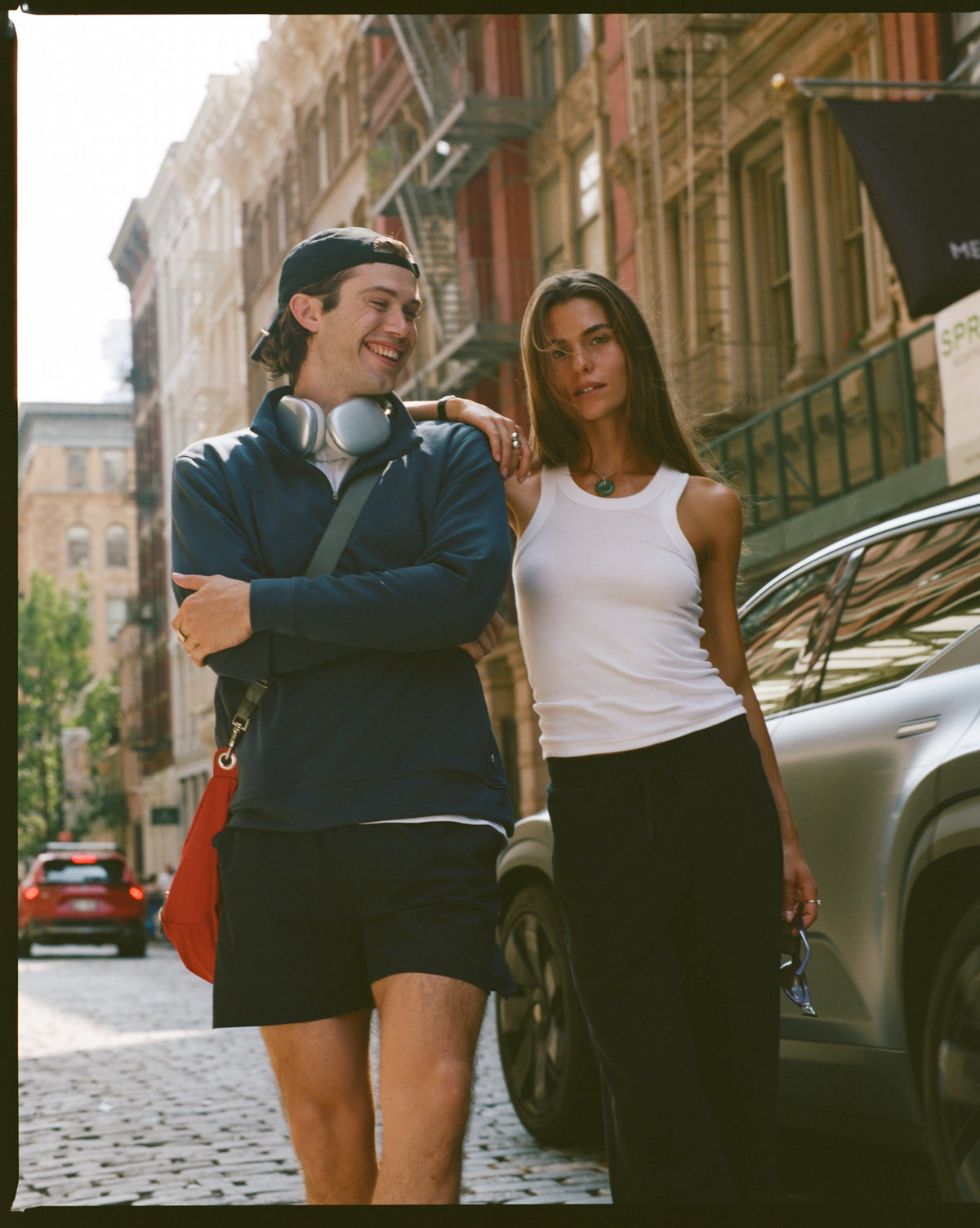 Couple in navy loungewear walking down a sunny city street