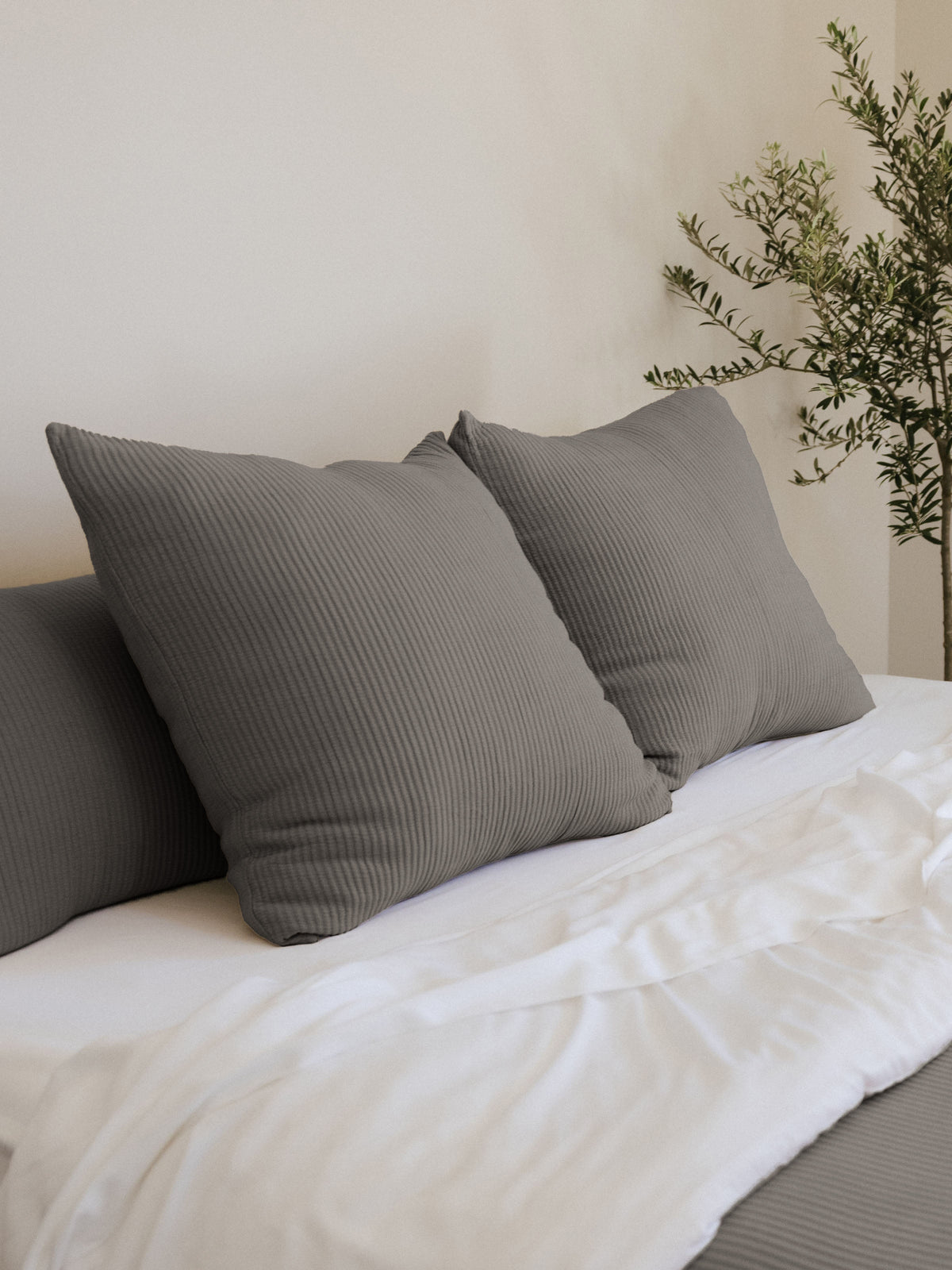 Charcoal coverlet shams on a white bed 