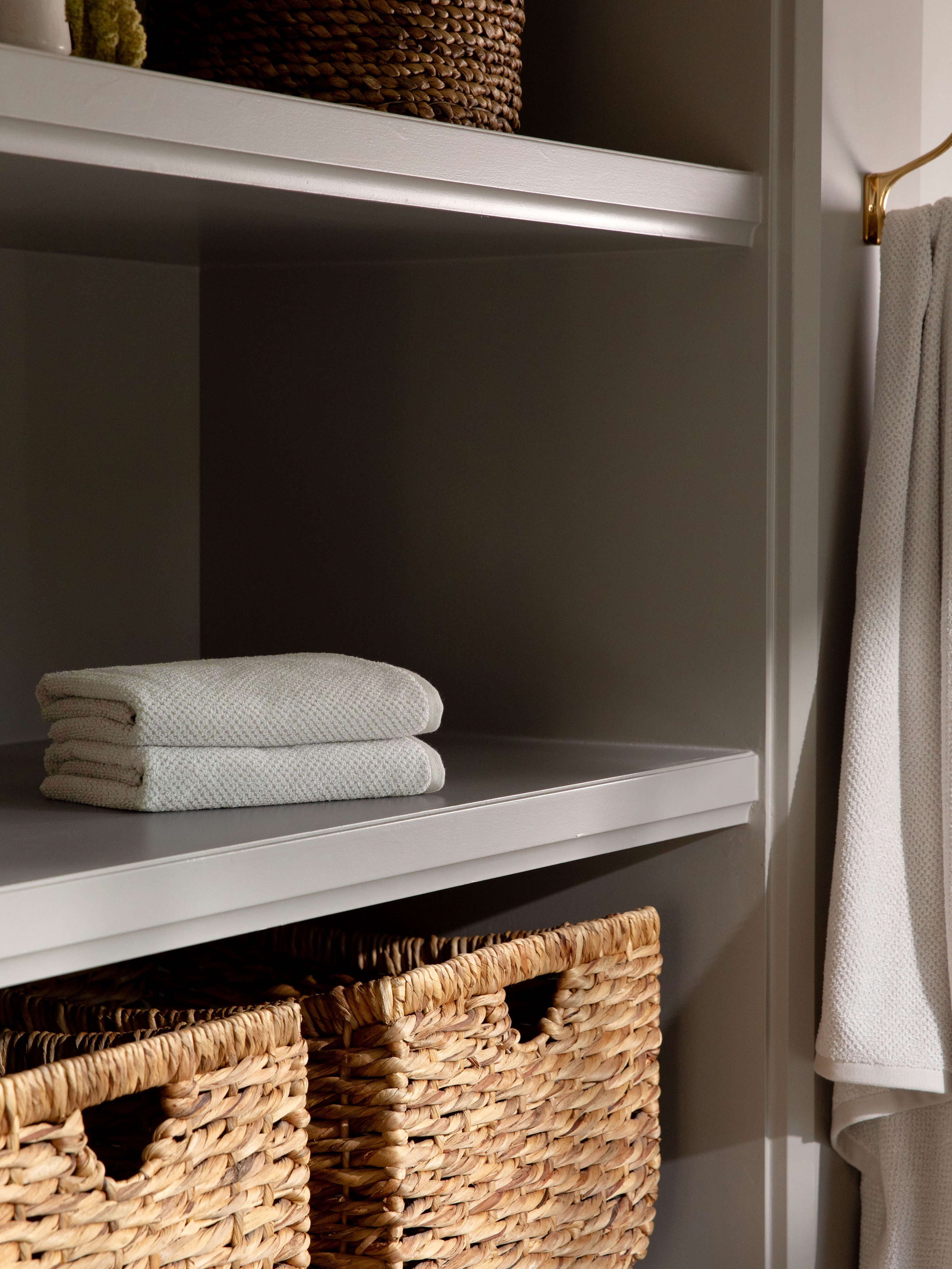 Nantucket Hand Towels in the color Heathered Light Grey. Photo of Nantucket Hand Towels taken with the hand towels resting on a shelf in a bathroom. |Color:Heathered Light Grey