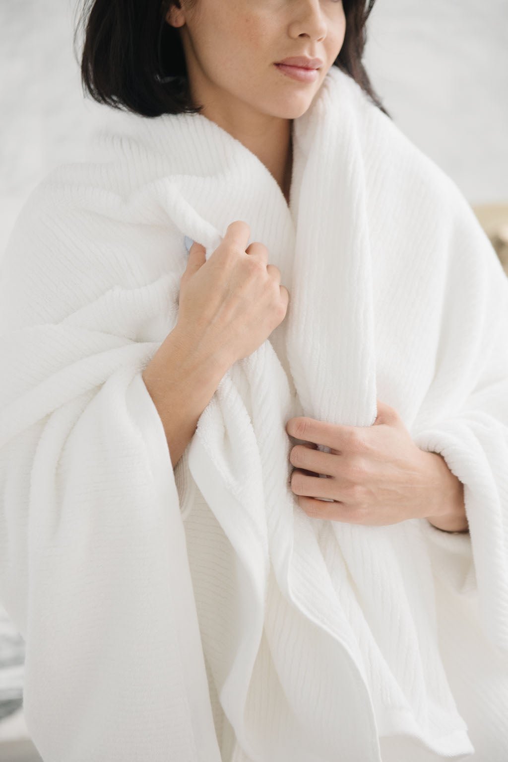 Ribbed Terry Bath Sheets in the color White. Photo of product taken in a bathroom as a woman wears the towel. |Color:White