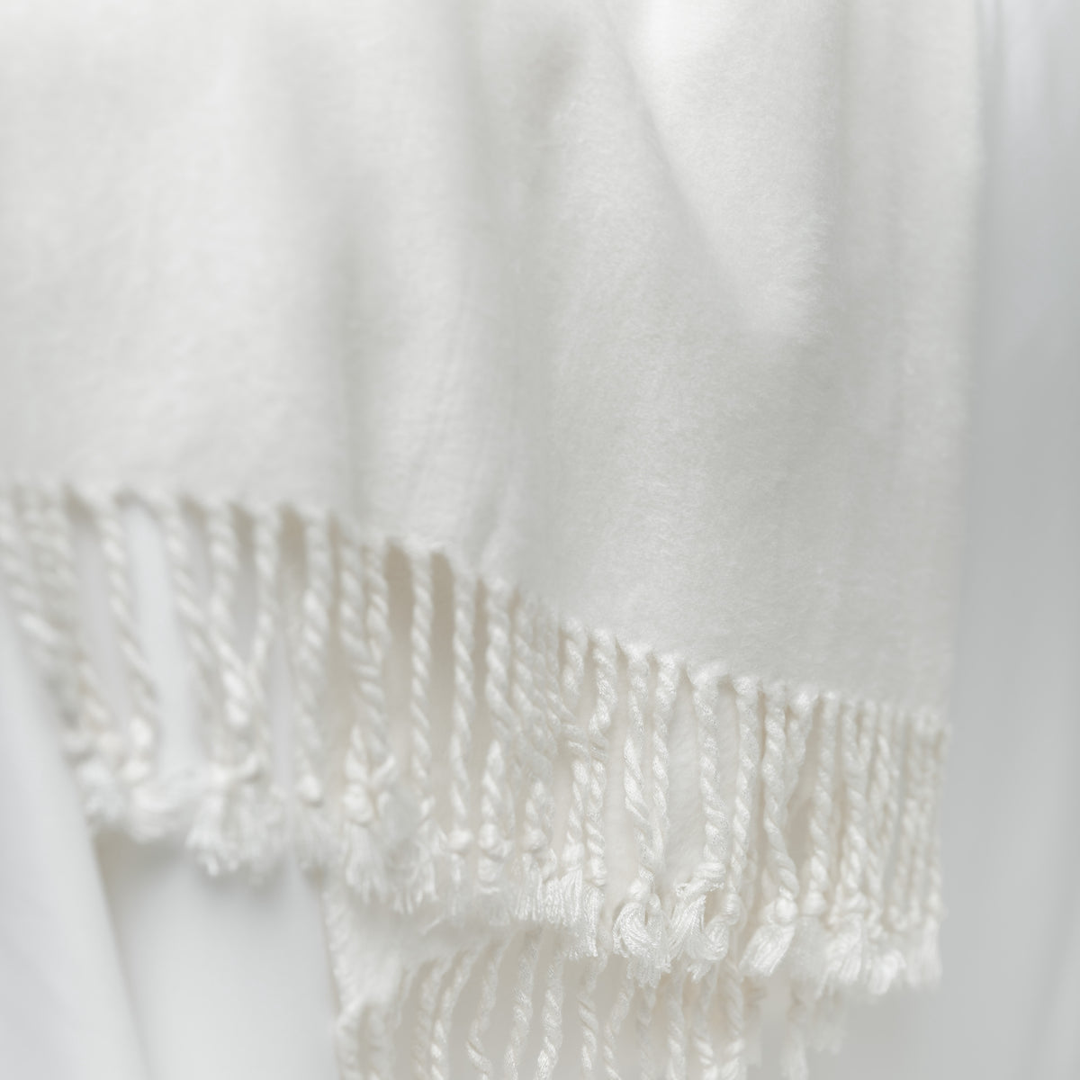 Close up of white throw blanket tassels 