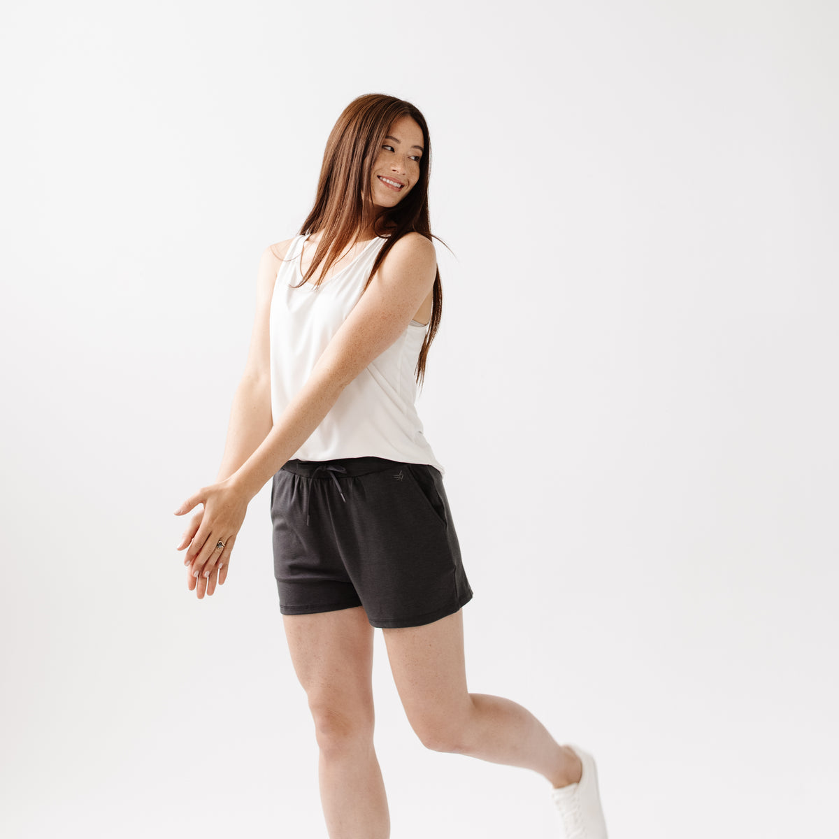 Person wearing Cozy Earth Brushed Bamboo Jogger Shorts in dark grey and a white top on a light background 
