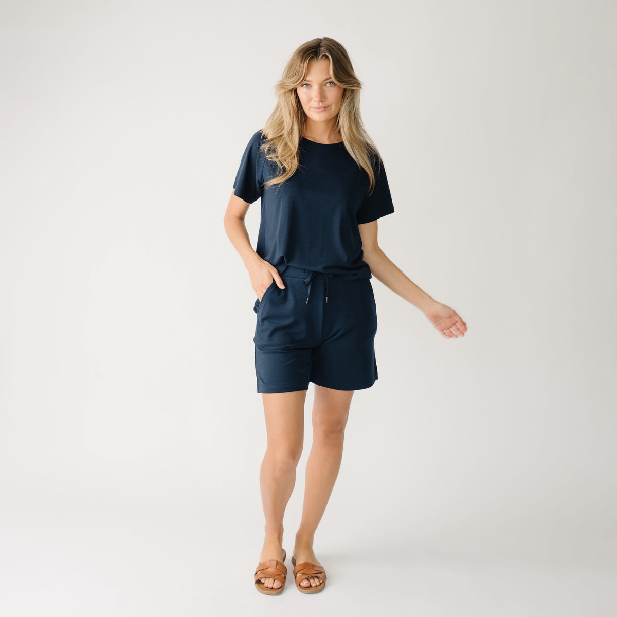 Woman wearing a navy t-shirt and navy Cozy Earth Brushed Bamboo Mid-Length Shorts shorts on a plain background 